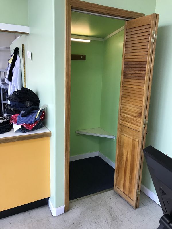 The shop’s fitting room, with a wooden louvered door standing open.